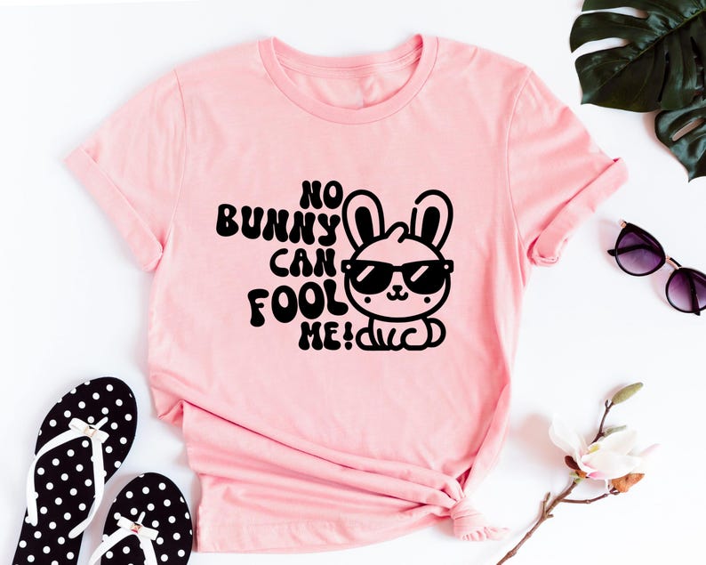 K&ouml;nnte beinhalten: Rosa T-Shirt mit einer schwarzen Grafik eines Kaninchens mit Sonnenbrille und dem Text "No bunny can fool me!"