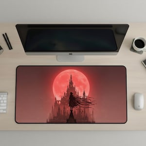 Puede incluir: Alfombrilla de ratón rectangular con la silueta de una persona frente a un castillo bajo una gran luna roja. El diseño está sobre un fondo degradado de tonos rojos y marrones. La alfombrilla tiene un borde negro.