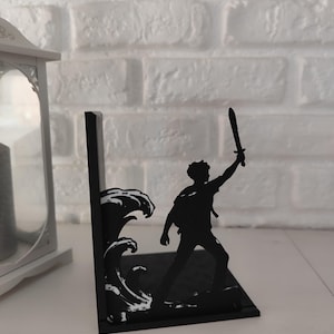 Sujetalibros de metal con diseño de tridente y olas inspirado en mitología griega, decoración temática para estantería de libros juveniles y sagas de fantasía épica, accesorio decorativo de semidiós griego y dioses del Olimpo, regalo para lectores de novelas de aventuras y coleccionistas de BookTok.