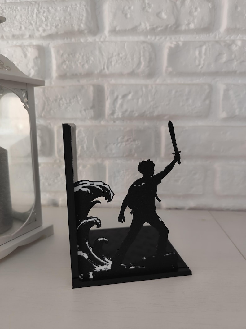 Sujetalibros de metal con diseño de tridente y olas inspirado en mitología griega, decoración temática para estantería de libros juveniles y sagas de fantasía épica, accesorio decorativo de semidiós griego y dioses del Olimpo, regalo para lectores de novelas de aventuras y coleccionistas de BookTok.