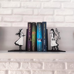 May include: Black metal bookends with a silhouette design of a girl in a dress, holding a book and a flower. The bookends are holding four Harry Potter books with colorful covers.