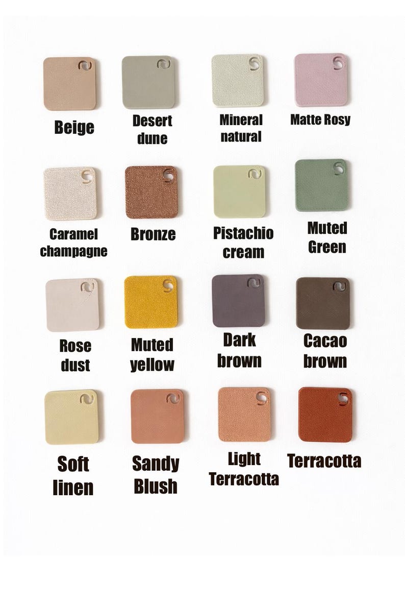 May include: Sixteen square colour swatches are displayed, showcasing a range of hues such as beige, desert dune, and matte rosy. Each swatch has a small hole and is labelled with its colour name in a sans-serif font. The colours vary from light to dark.
