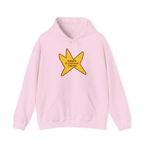 May include: A light pink hoodie with a front pocket and a drawstring hood. The hoodie features a yellow star graphic with the text "MANAGED MY EXECUTIVE FUNCTION" in black. The hoodie is made of a soft material.