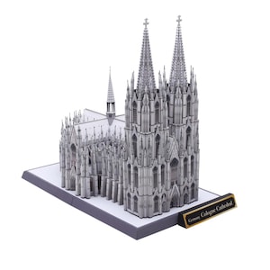 May include: A detailed model of Cologne Cathedral, a famous landmark in Germany. The model is made of white paper and features intricate details of the cathedral's architecture, including its twin spires and stained glass windows.