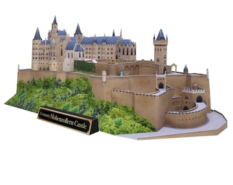 Peut inclure: Un modèle en papier détaillé du château de Hohenzollern en Allemagne. Le château est fait de papier brun et est entouré d'un mur de pierre gris. Le château est entouré d'arbres et de buissons verts. Le modèle est sur un fond blanc. Le texte "Allemagne Château de Hohenzollern" est imprimé sur une plaque noire devant le modèle.