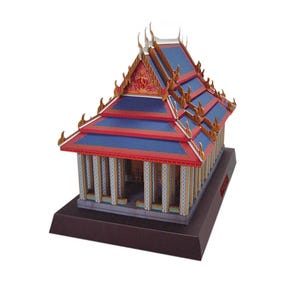 以下が含まれることがあります： タイの寺院のミニチュア模型。屋根は青色で、赤と金の装飾が施されています。寺院には白い柱があり、濃い茶色の台座に置かれています。伝統的な建築様式を詳細に表現したモデルです。