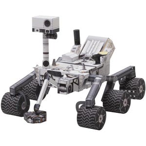May include: A white and grey paper model of a Mars rover, with detailed construction including articulated arms, wheels, and a camera mast. The rover has a textured surface and is designed to resemble the real-life vehicle.