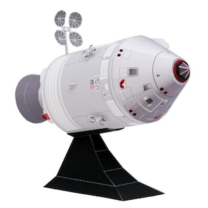 May include: A white ceramic mug with a black handle and the text "But First, Coffee" in a bold, black font. The mug is filled with a dark liquid, likely coffee, and sits on a light-colored surface.