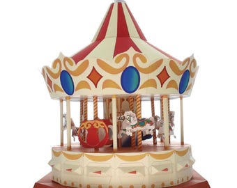May include: A miniature carousel with a red and cream-colored canopy, adorned with gold accents and blue and orange shapes. The carousel features several white horses and is topped with a small angel figurine. The base is red.
