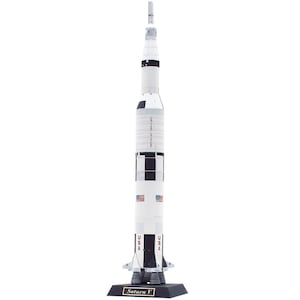 Può includere: Un modello dettagliato del razzo Saturn V, prevalentemente bianco con dettagli neri e argento. Il modello presenta la bandiera USA e testo, in piedi su una base nera con "Saturn V" stampato. Un ottimo oggetto da collezione.