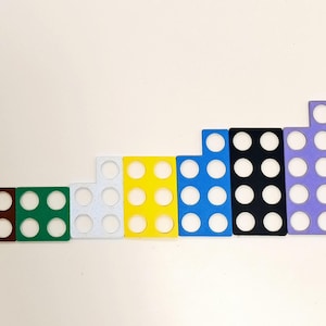 Op de afbeelding: Een set van tien kleurrijke telblokken, elk met een ander aantal cirkels. De blokken zijn gerangschikt in een rij van klein naar groot, met het kleinste blok grijs en het grootste blok rood.