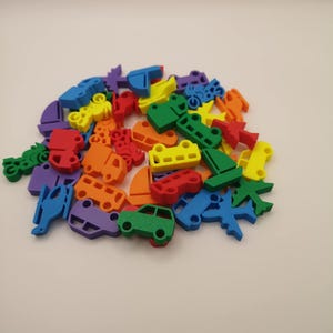 May include: A collection of colorful foam toy vehicles, including cars, trucks, motorcycles, airplanes, and boats. The toys are in various bright colors such as red, green, blue, yellow, orange, and purple. These toys are likely for children.