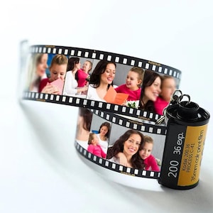 May include: A black and yellow film canister keychain with a photo strip of a family. The film canister has the text "200 36 exp. Kodak 200.36 PROCESS C-41 35mm colour print film" printed on it.