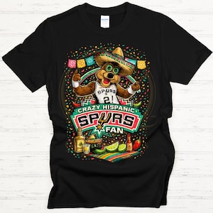 May include: Black t-shirt featuring a cartoon bear wearing a sombrero and a Spurs jersey. The design includes the text "Crazy Hispanic Spurs Fan" with colorful confetti and festive elements like limes, tequila, and chili peppers.