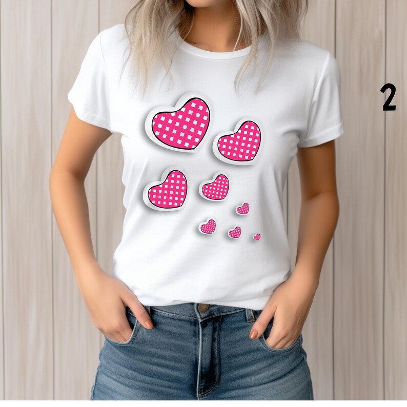 May include: White t-shirt featuring a design of pink hearts with a white grid pattern. The hearts vary in size and are arranged on the front of the shirt. The shirt is made of a soft material.