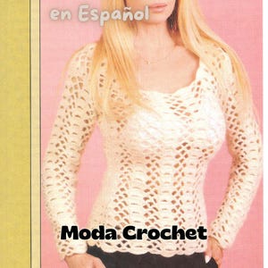 May include: A white crochet top with a lacy pattern. The top has long sleeves and a scoop neckline. The text "Moda Crochet" is printed on the front of the top.