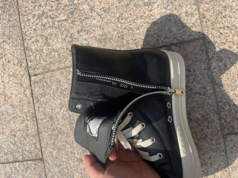 May include: A black high-top sneaker with a white rubber sole and white laces. The shoe features a side zipper closure with silver hardware. The interior zipper flap displays the text U 8800 44 and MADE IN ITALY.