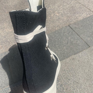 May include: Black canvas high-top trainers with white laces and a thick white platform sole.