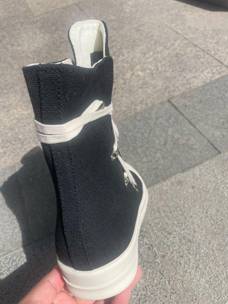 May include: Black canvas high-top trainers with white laces and a thick white platform sole.