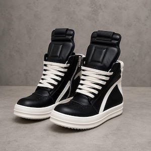 May include: Black high-top sneakers with white accents and laces. The sneakers feature a side zipper and a thick white sole. The design includes a padded tongue and a strap at the top of the shoe.