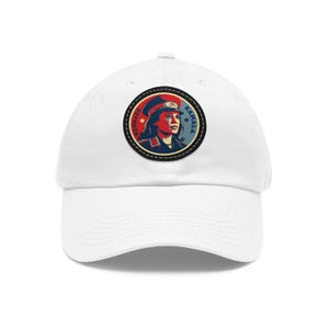 May include: White baseball cap with a red, white, and blue embroidered patch featuring a woman in a military uniform with the text "Komrade Kamala" on the patch.