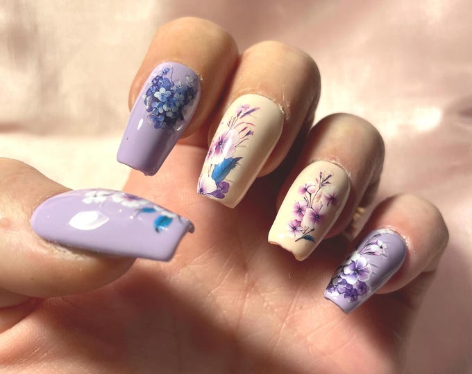 24-piece kit. Pastel purple and orange with purple flowers. Sizes 0 to 9. False nails, press-on nails. Reusable. Glossy finish.