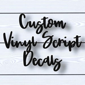 May include: Black script text on a white wood background reads "Custom Vinyl Script Decals." The text is in a cursive font, with a shadow effect. The background is made of white painted wooden planks.