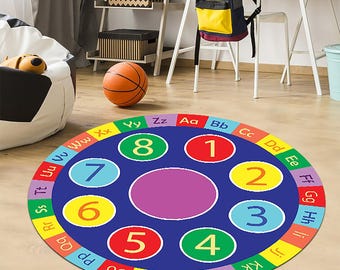 May include: A round educational rug with a blue center featuring numbers 1-8 in colorful circles. The outer ring displays the alphabet in various colors. An orange basketball sits nearby, suggesting a playroom setting.