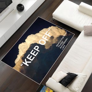 Può includere: Un tappeto nero e bianco con un design a nuvole e il testo "KEEP OFF" in bianco. Il testo "IKEA® c/o Virgil Abloh™™™" è incluso anche in bianco. Il tappeto è su un pavimento di legno.
