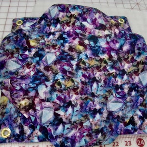 May include: A fabric panel with a colorful print of purple, blue, and white crystals. The fabric has grommets on the edges for hanging.