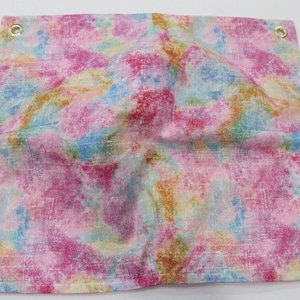 May include: A pink, blue, and yellow fabric with a tie-dye pattern. The fabric has four brass grommets in the corners.