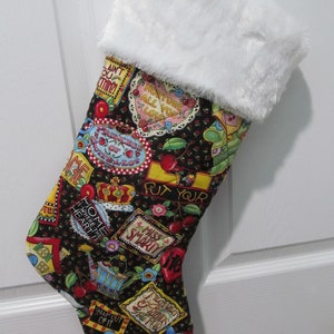 May include: A Christmas stocking with a black background covered in colorful patches with text and images of cherries, teapots, and crowns. The top of the stocking is trimmed with white faux fur.