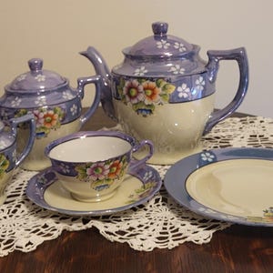 May include: A vintage tea set with a blue and white floral design. The set includes a teapot, creamer, sugar bowl, teacup, and saucer.