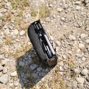 Pu&ograve; includere: Un multiutensile nero con una variet&agrave; di strumenti, tra cui cacciaviti, chiavi e un coltello. Il multiutensile &egrave; chiuso e ha una custodia in pelle nera.