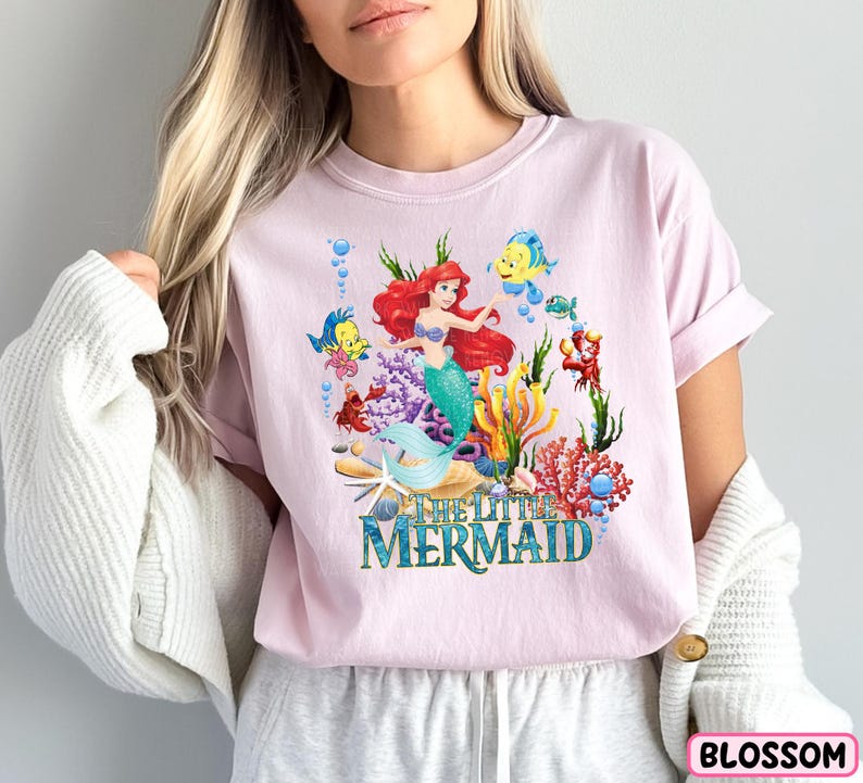 a woman wearing a pink shirt with a mermaid on it