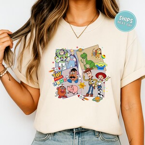 A person wearing a white t-shirt with a collage of various characters from the Toy Story franchise, including Buzz Lightyear, Woody, and other beloved characters.