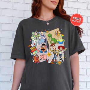 A person wearing a black t-shirt with a colorful graphic design featuring characters from the Toy Story franchise.