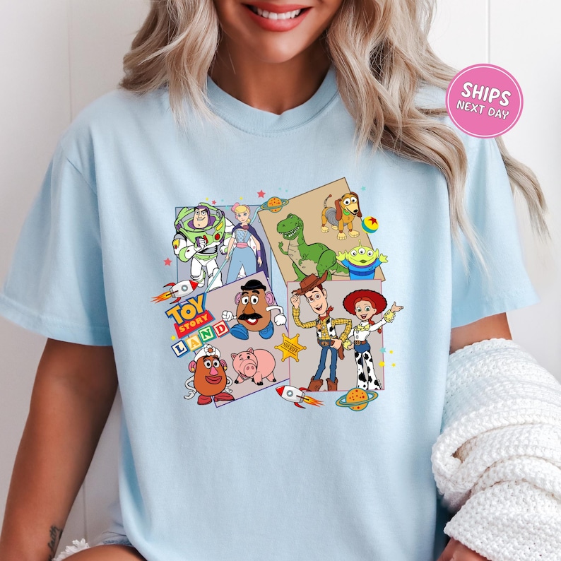 A woman wearing a light blue t-shirt with a collage of various characters from the Toy Story franchise, including Woody, Buzz Lightyear, and other beloved characters.