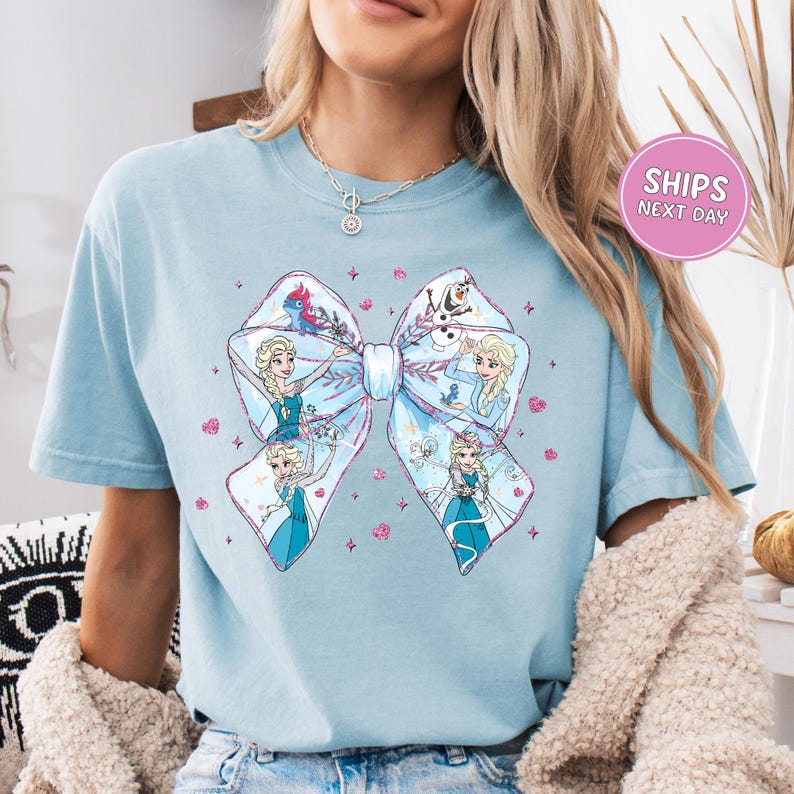 A woman wearing a light blue t-shirt with a large bow design featuring characters from the Disney movie Frozen.