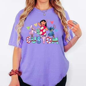 A woman wearing a purple t-shirt with a cartoon character design and the word "CUSTOM" printed on it.