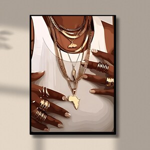 May include: A close-up of a person's hands wearing multiple gold rings and a layered gold necklace with an Africa-shaped pendant.
