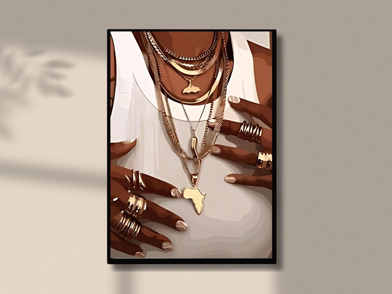 May include: A close-up of a person's hands wearing multiple gold rings and a layered gold necklace with an Africa-shaped pendant.