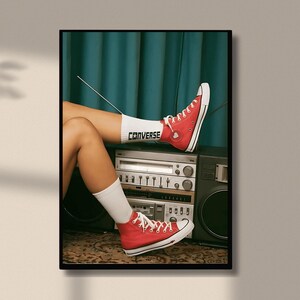 May include: A woman wearing red Converse sneakers with white socks. The socks have the word "Converse" written on them. The woman is sitting on a vintage stereo system with a microphone.