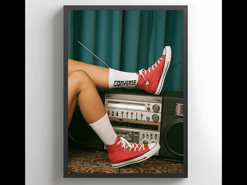 May include: A woman's legs are resting on a vintage stereo system. She is wearing red Converse sneakers with white socks that say "Converse" on them. The stereo has a cassette player, a tuner, and a record player.