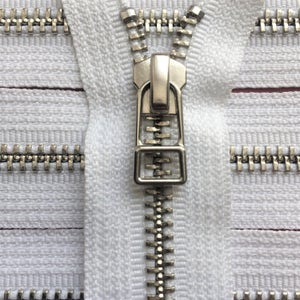 May include: Close-up of a white zipper with a silver metal pull and teeth. The zipper is partially open, revealing the teeth and the white fabric beneath. The metal pull is rectangular with a square opening.