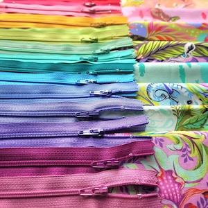 May include: A rainbow assortment of colourful zippers arranged in a vertical stack. The zippers are arranged from red to purple, with each colour having a different shade. The zippers are all closed and have a metal slider.