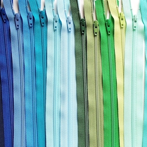 May include: A variety of zipper pulls in different shades of blue and green. The zipper pulls are arranged in a row, with the blue pulls on the left and the green pulls on the right.