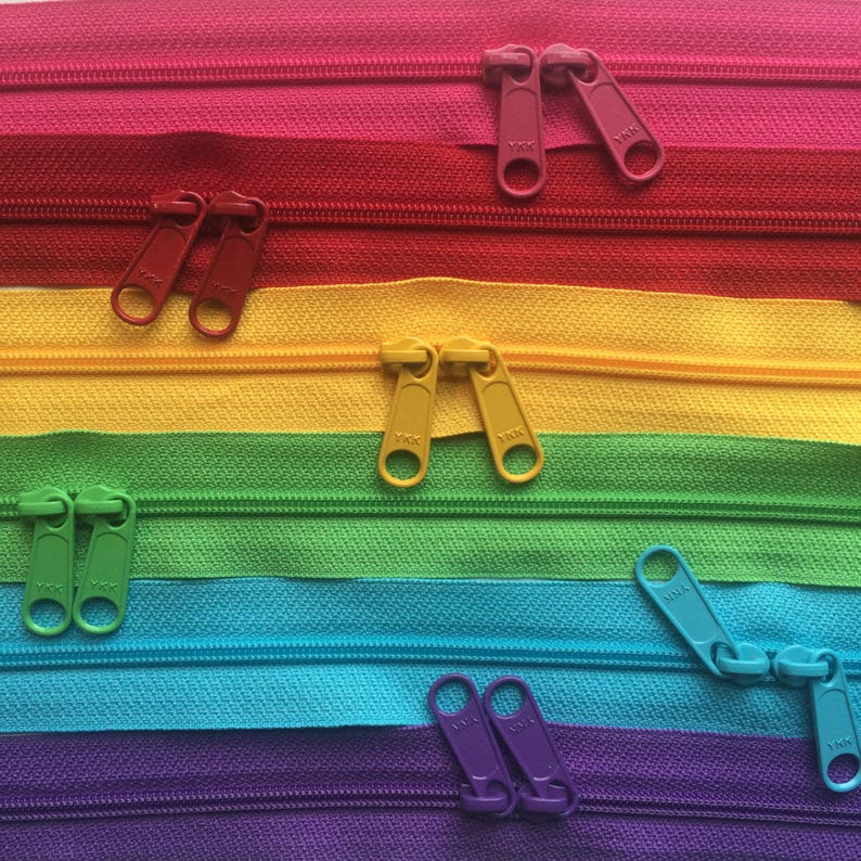 May include: Assortment of colorful zipper tapes with metal zipper pulls. The zipper tapes are red, yellow, green, blue, and purple. The zipper pulls are silver.