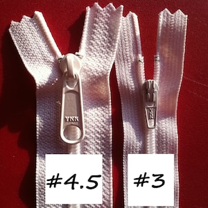 May include: Two white zippers with metal sliders. The zipper on the left is labelled #4.5 and the zipper on the right is labelled #3.