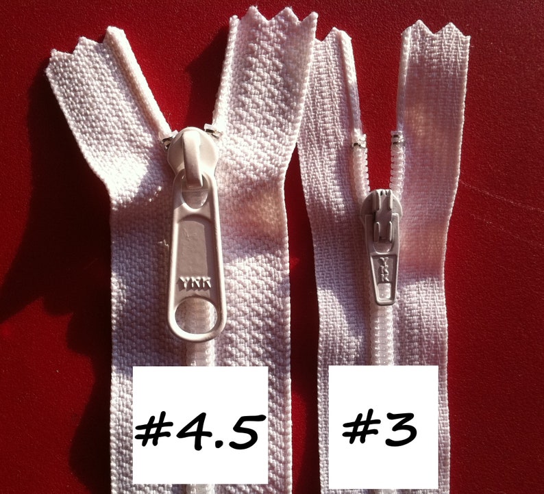 May include: Two white zippers with metal sliders. The zipper on the left is labelled #4.5 and the zipper on the right is labelled #3.